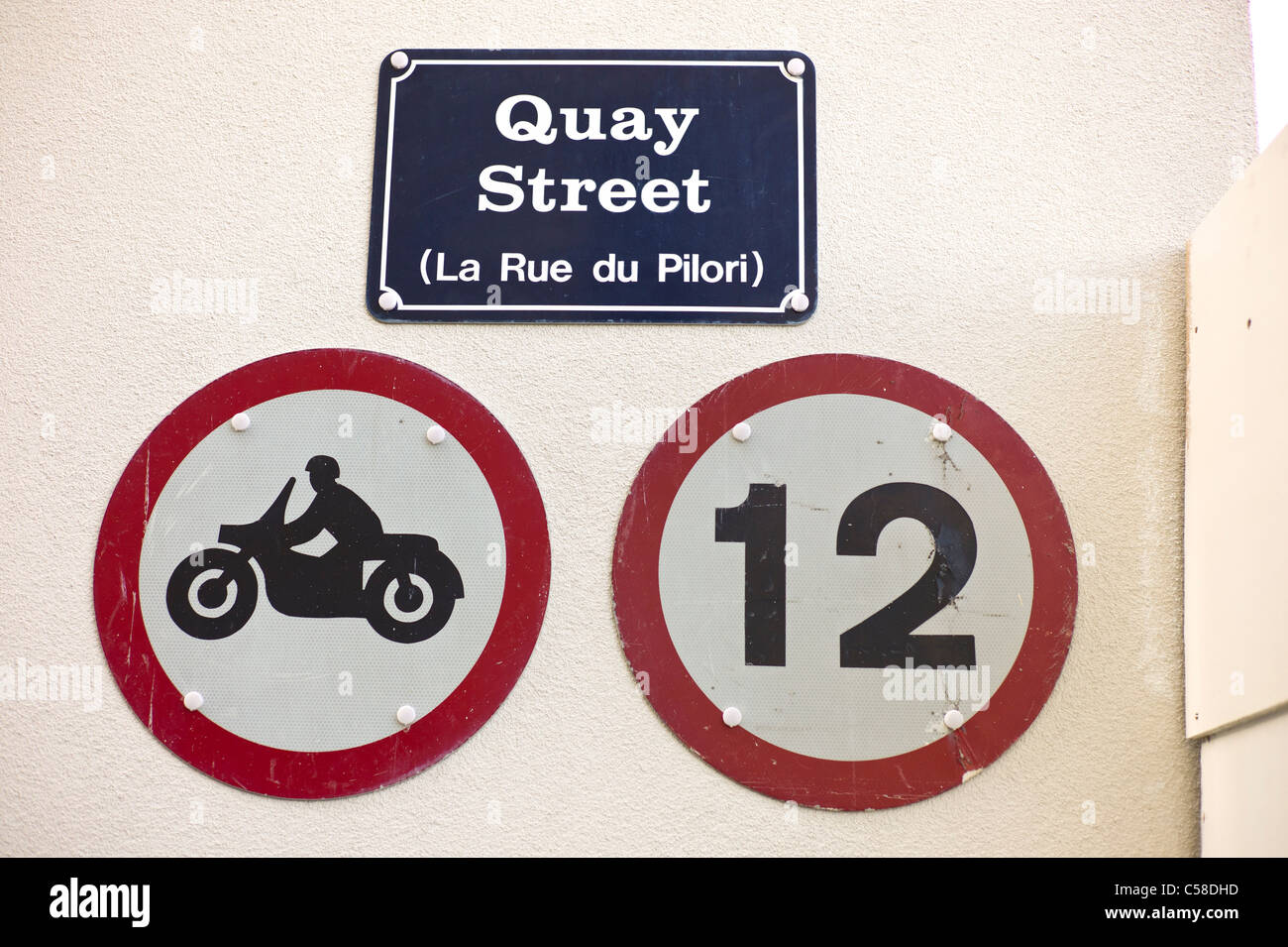 I segni sulla parete in Guernsey mostra limite bassa velocità in città e di divieto di cicli del motore in Quay Street Foto Stock