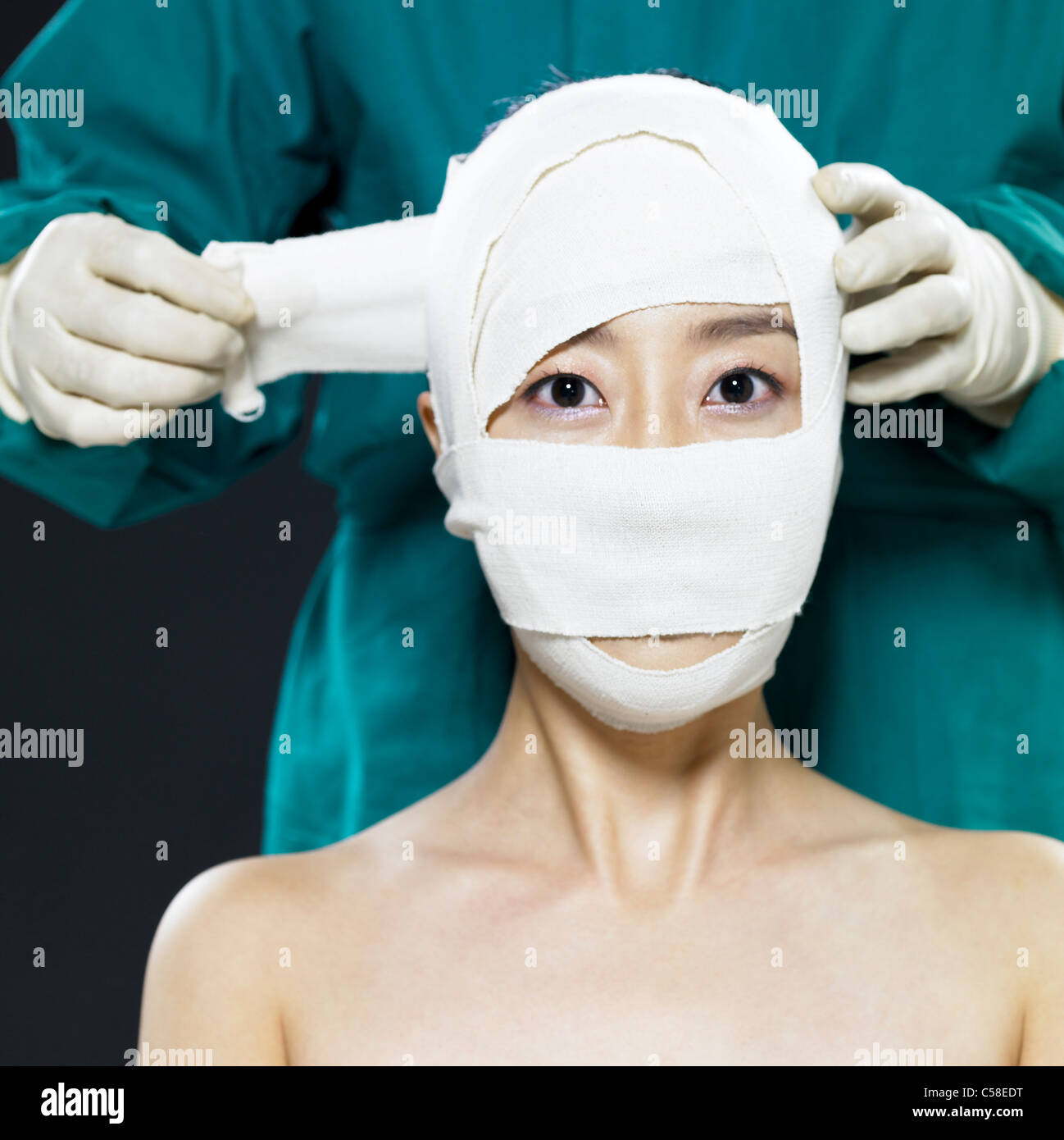 Close-up di medico l'applicazione di bendaggi sul volto di donna Foto Stock