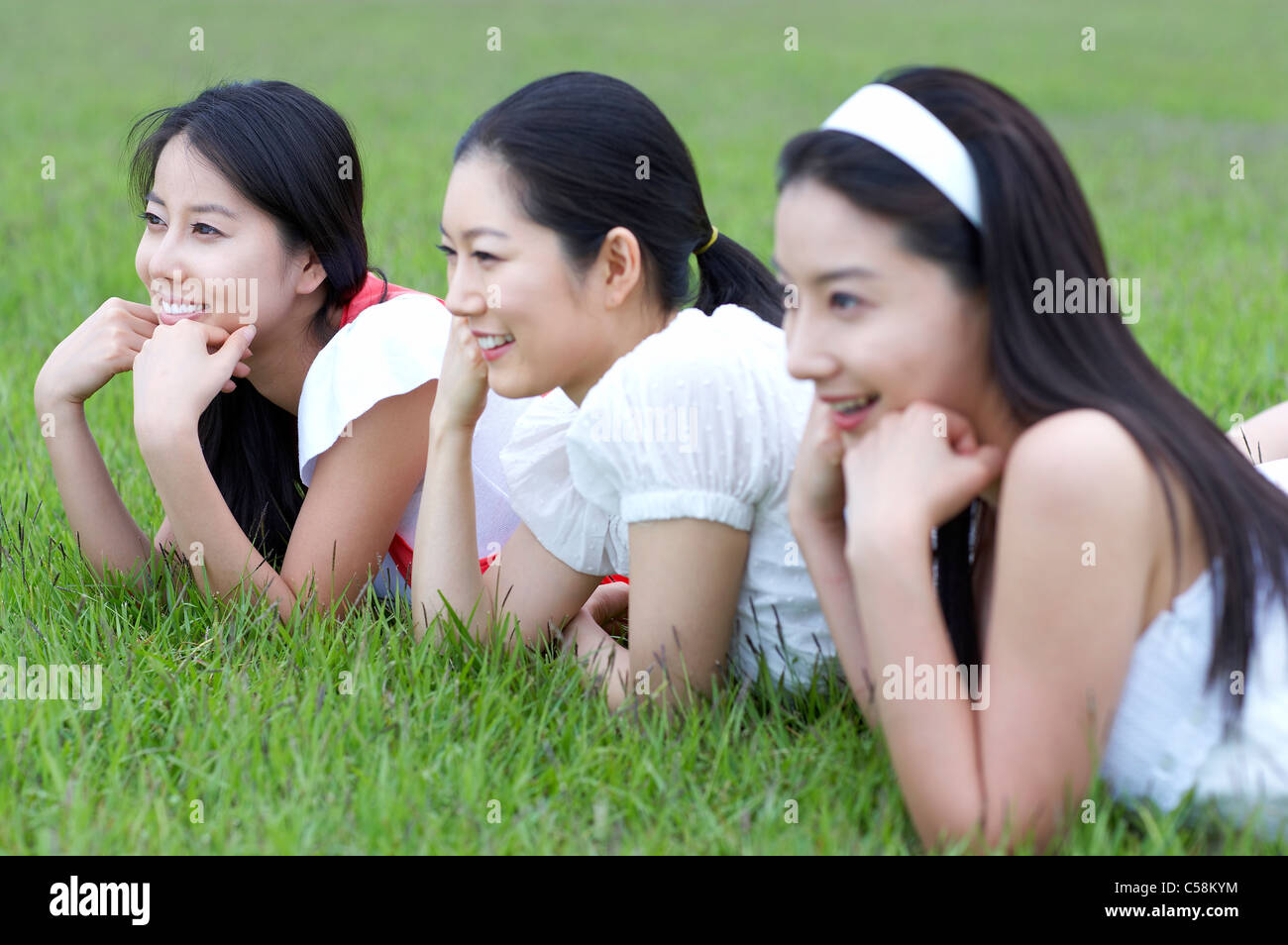 Vista laterale di giovani donne sdraiati sull'erba Foto Stock