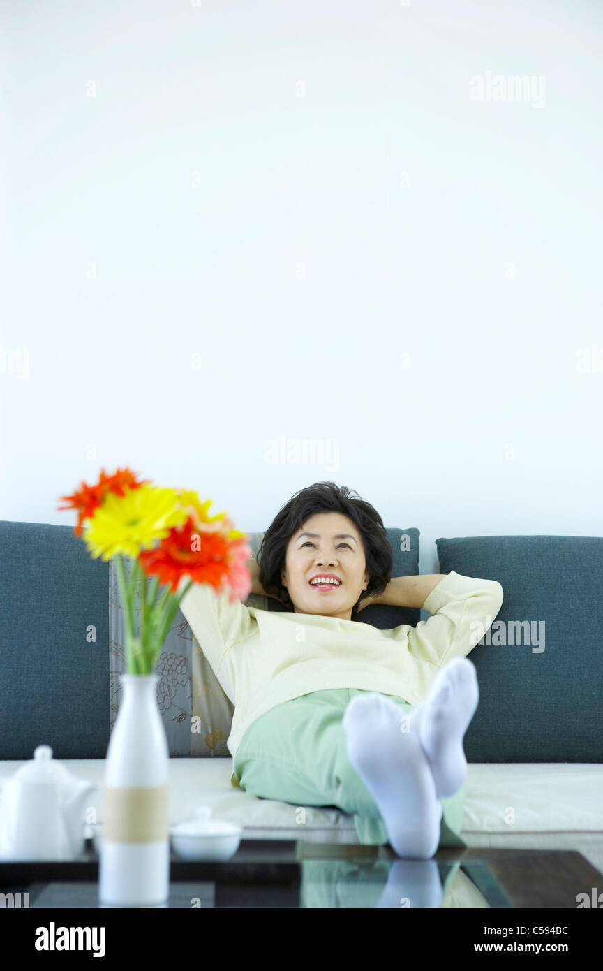 Senior donna seduta sul divano Foto Stock