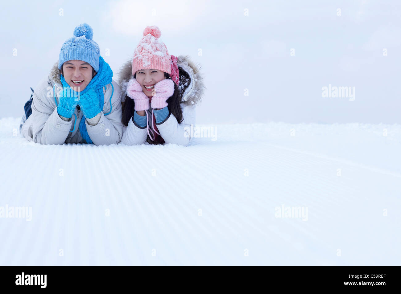Giovane uomo e donna godendo sulla terra incappucciate di neve Foto Stock