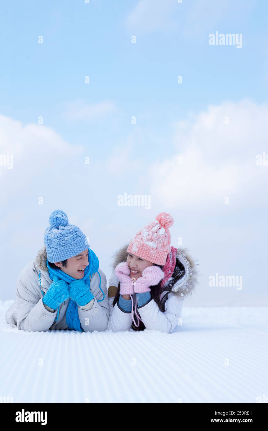 Giovane uomo e donna godendo sulla terra incappucciate di neve Foto Stock