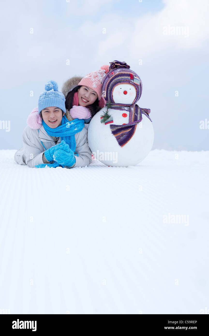 Giovane uomo e donna godendo sulla terra incappucciate di neve Foto Stock