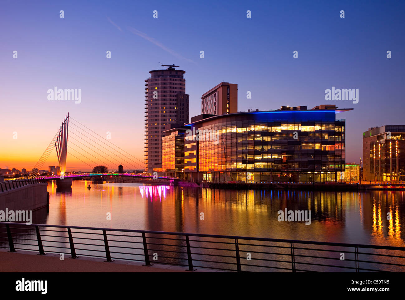 Media City e sospensione ponte illuminato al crepuscolo, Salford Quays, Greater Manchester, Inghilterra Foto Stock