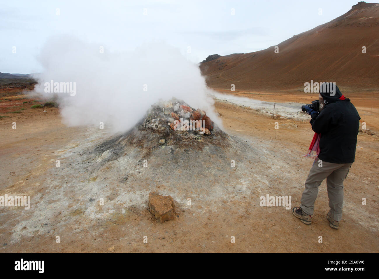 L'uomo prendendo un close up foto della cottura al vapore geotermico o sfiato fumarola a Hverarond vicino a Myvatn Nord Islanda Foto Stock