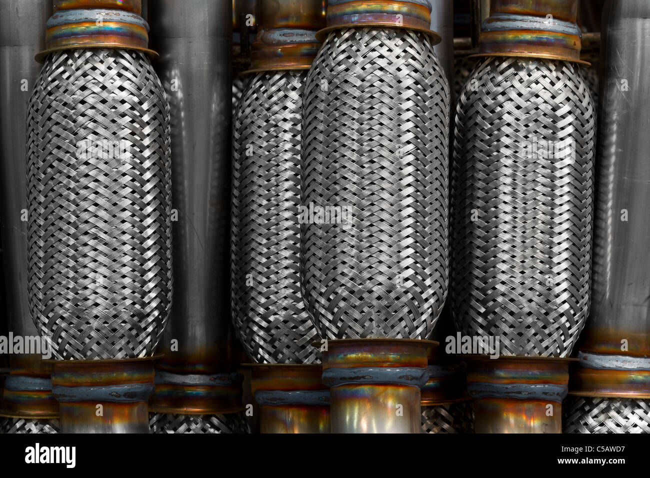 Una vista ravvicinata di più componenti cilindrici in metallo con un motivo a trama stretta. Ciascun cilindro è chiuso su entrambe le estremità con flange metalliche solide che mostrano segni di saldatura, tra cui Foto Stock