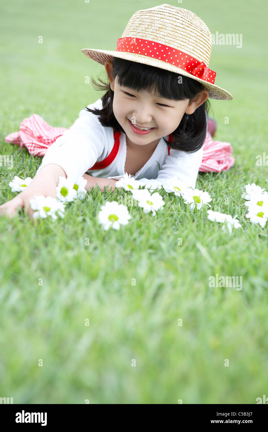 Sorridente ragazza distesa sul prato con fiori nella parte anteriore Foto Stock