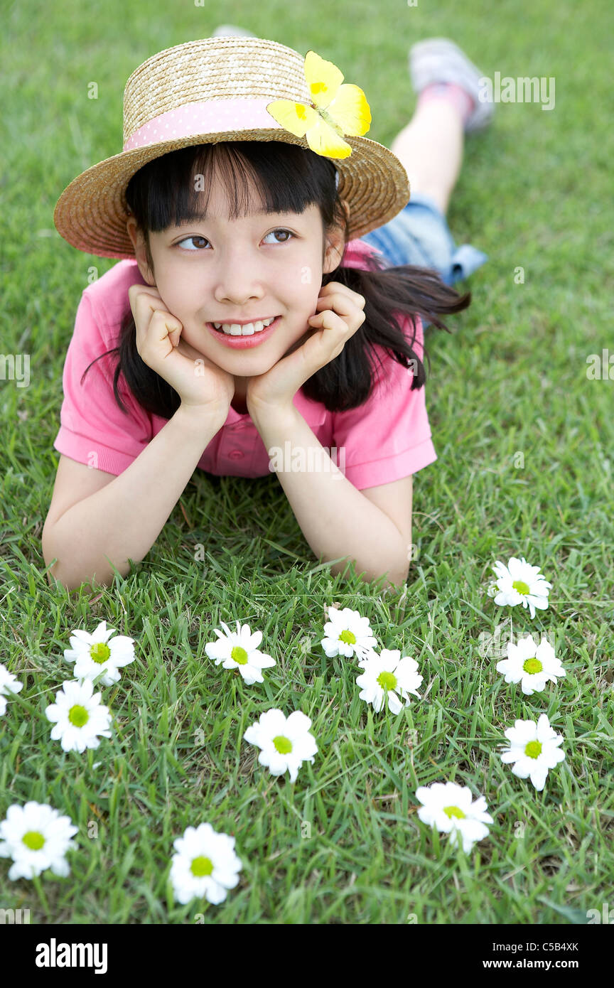 Ragazza distesa sul prato con fiori in primo piano Foto Stock