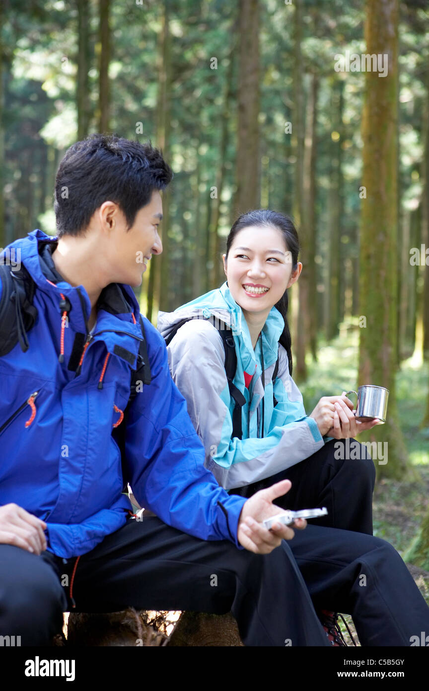 Giovane seduto sul log in foresta Foto Stock