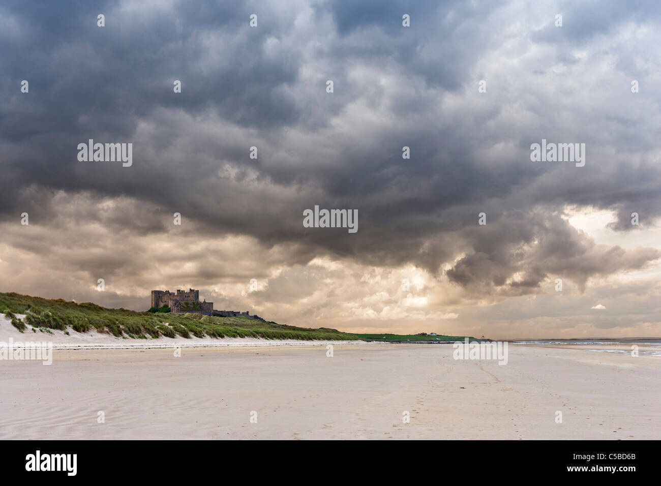 Vista lungo la spiaggia al castello di Bamburgh sulla costa di Northumberland, North East England, Regno Unito Foto Stock