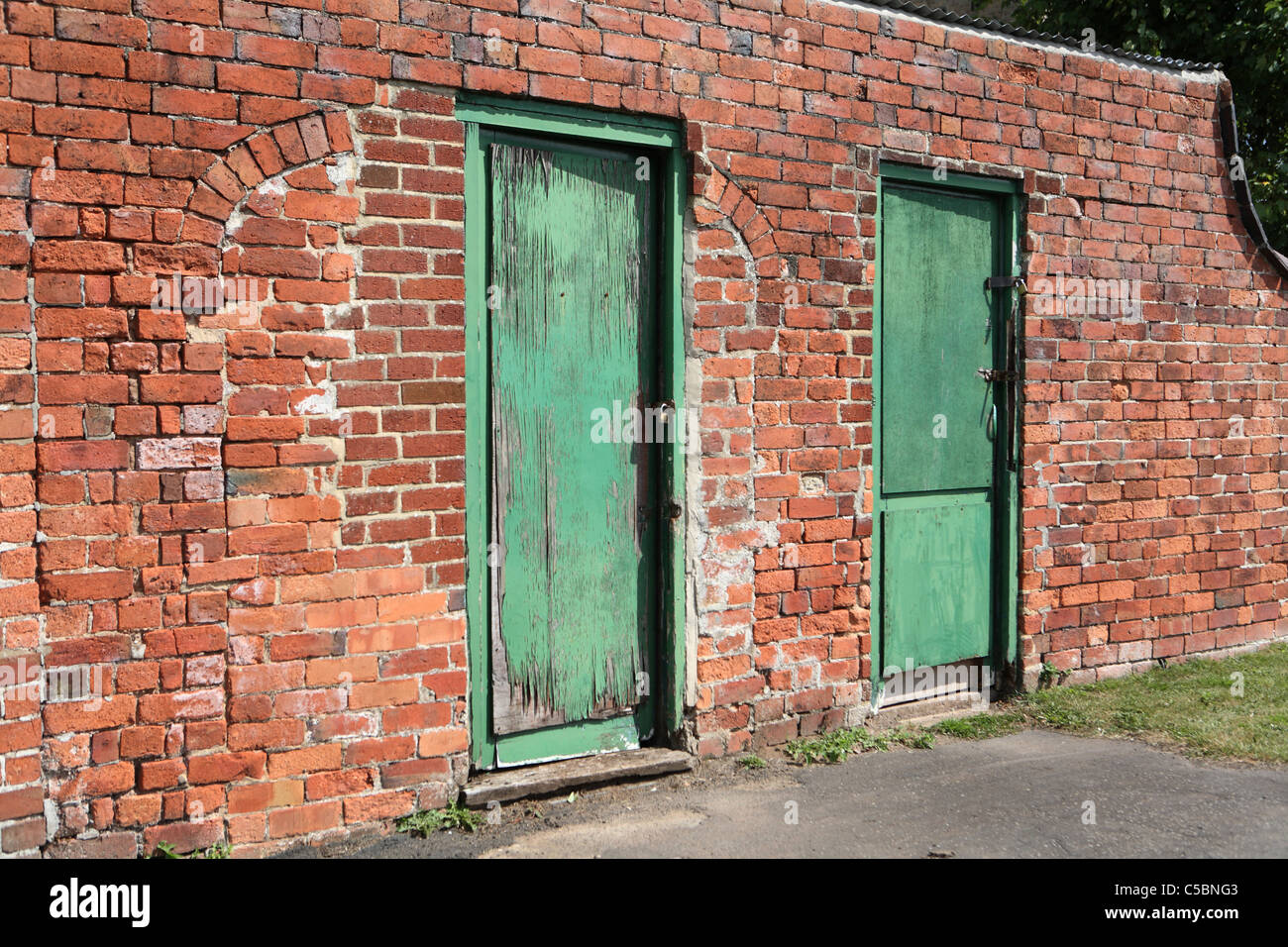 Due porte verdi in un vecchio muro di mattoni Foto Stock