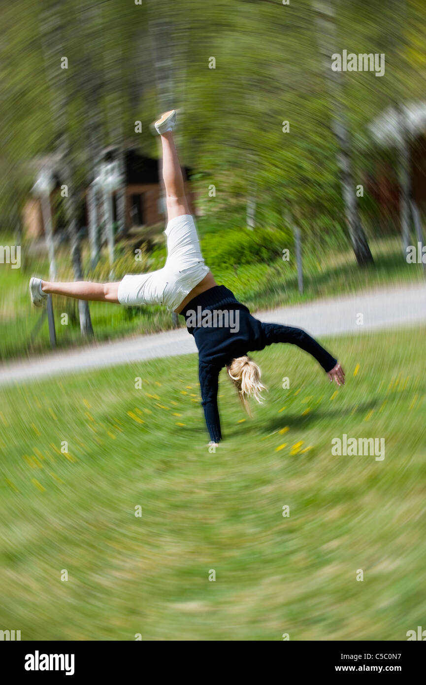 Vista posteriore di una ragazza adolescente facendo il handstand sull'erba Foto Stock