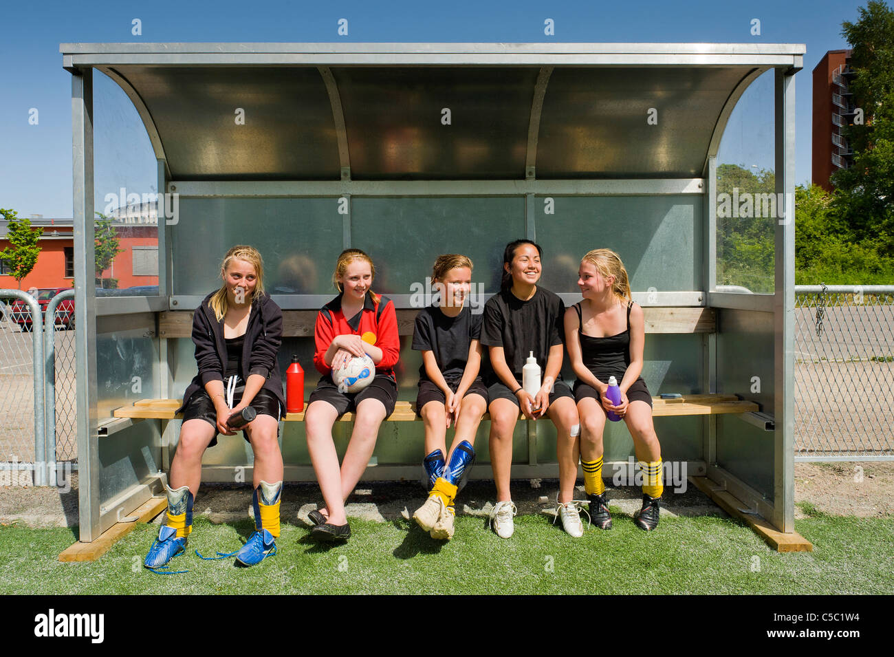 Cinque ragazze calcio seduti fianco a fianco sul banco di lavoro Foto Stock