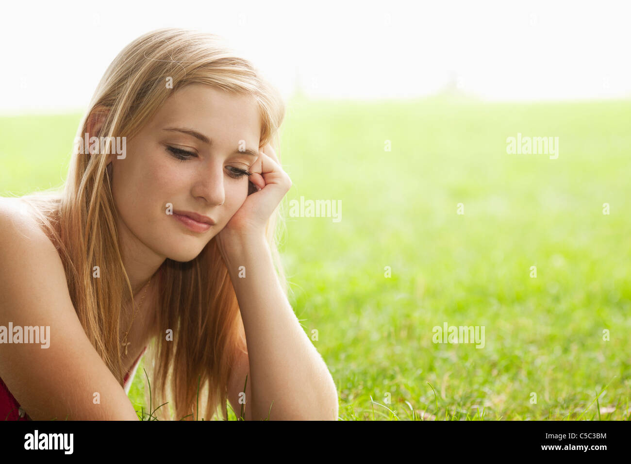 Grave Caucasian ragazza seduta in erba Foto Stock