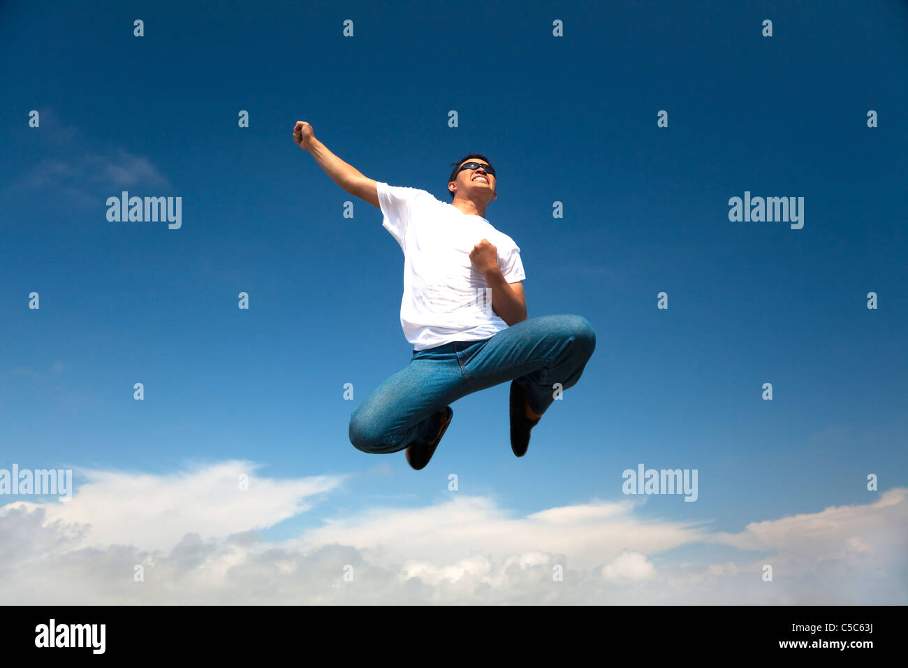 Felice giovane uomo jumping e il Cielo di estate Foto Stock