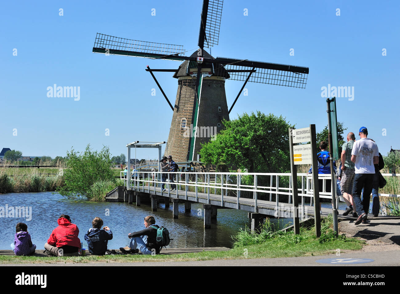 I turisti in visita a pietra il mulino a vento di drenaggio a Kinderdijk, un sito Patrimonio Mondiale dell'UNESCO a South Holland, Paesi Bassi Foto Stock