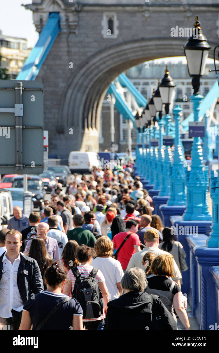 La gente che camminava lungo il marciapiede affollato su approcci per il Tower Bridge di Londra Foto Stock