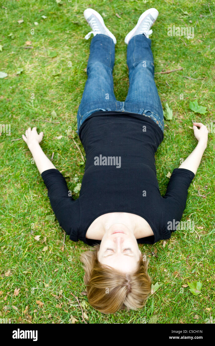 A piena lunghezza Ritratto di una donna che giace in posizione supina sull'erba, London, England, Regno Unito Foto Stock