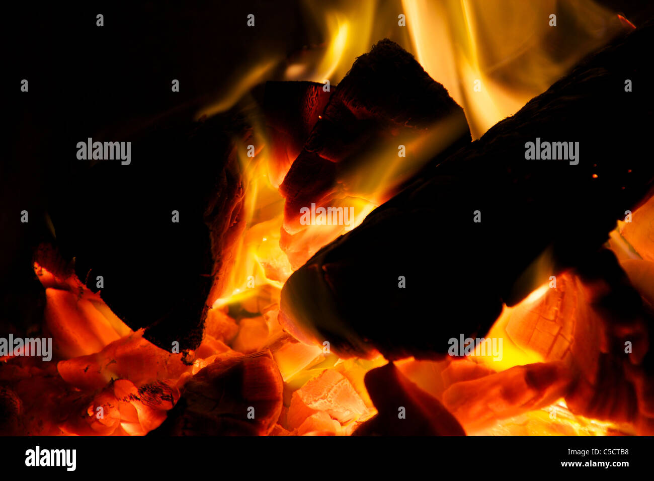 Spaccare la legna brucia in carboni caldi con fiamme di colore ambra Foto Stock