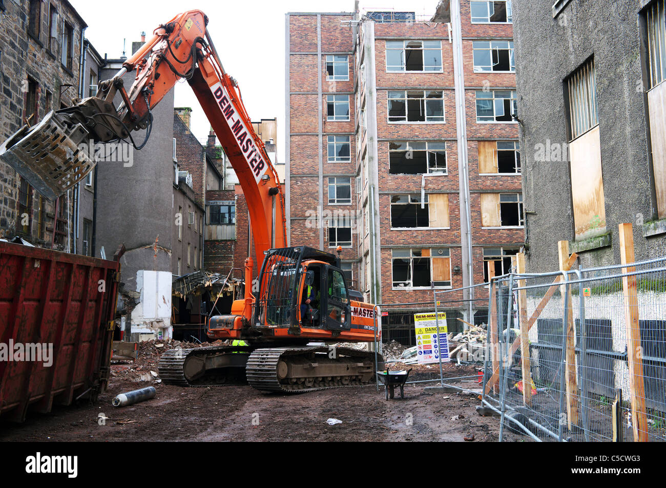 Digger essendo utilizzato per eliminare le macerie e detriti dalla demolizione di un sito. Glasgow, Scotland, Regno Unito Foto Stock