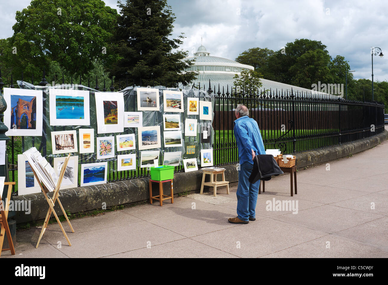 Uomo che guarda un'arte vendita allegata per le ringhiere presso i giardini botanici, Queen Elizabeth Drive, Glasgow, Scotland, Regno Unito Foto Stock
