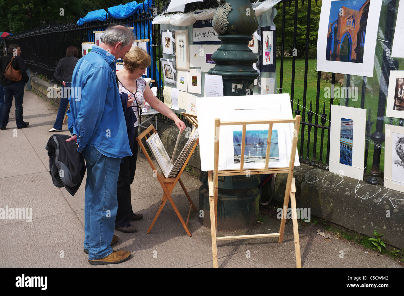 Uomo e donna che guarda a stampe d'arte presso un'openair art display e scegliendo tra una selezione di Glasgow, Scotland, Regno Unito Foto Stock