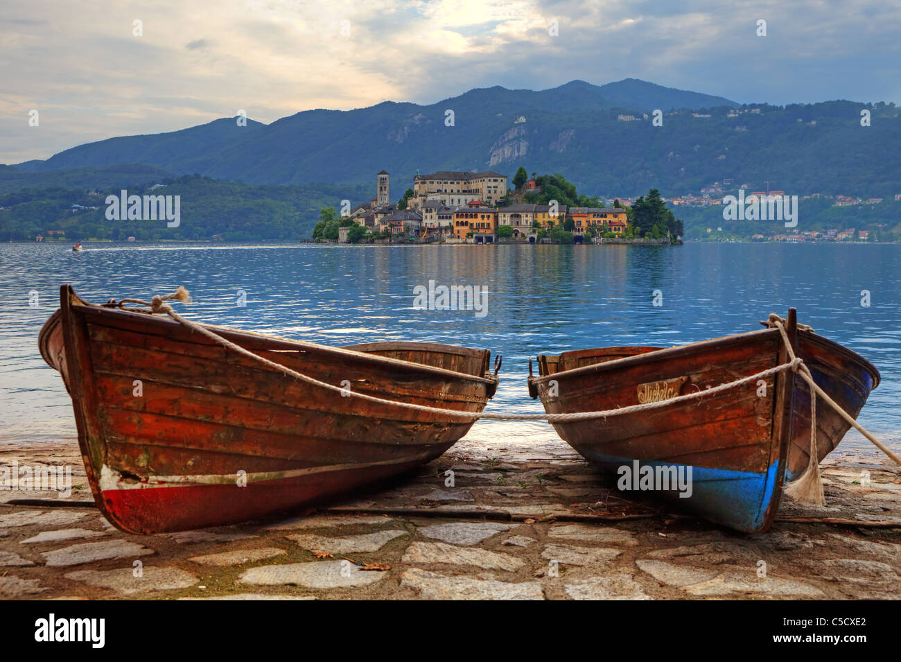 L'isola di San Giulio sul Lago d'Orta con due vecchie barche di legno in primo piano Foto Stock