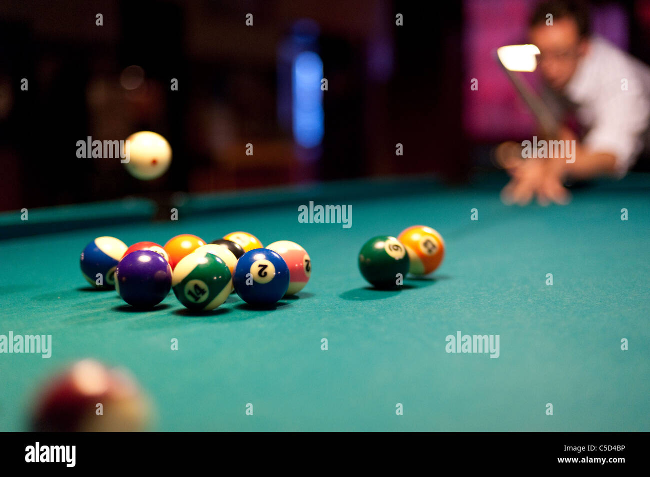 Giovane uomo giocare palla otto tavoli da biliardo in un bar Foto Stock
