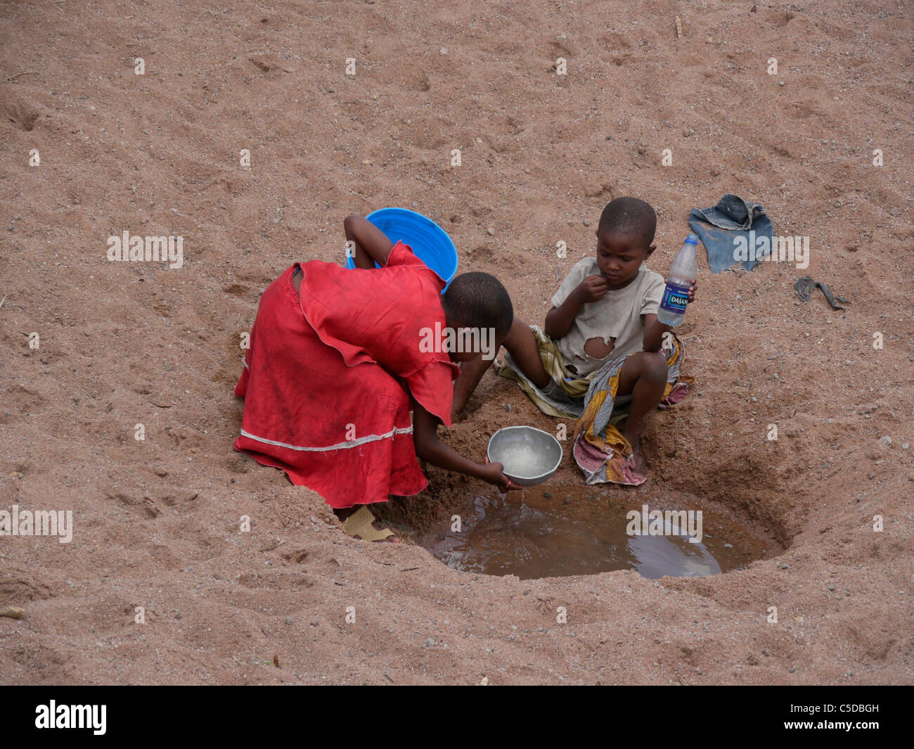 In Tanzania i bambini raccolta di acqua da un asciugò il letto del fiume vicino Shinyanga. fotografia di Sean Sprague Foto Stock