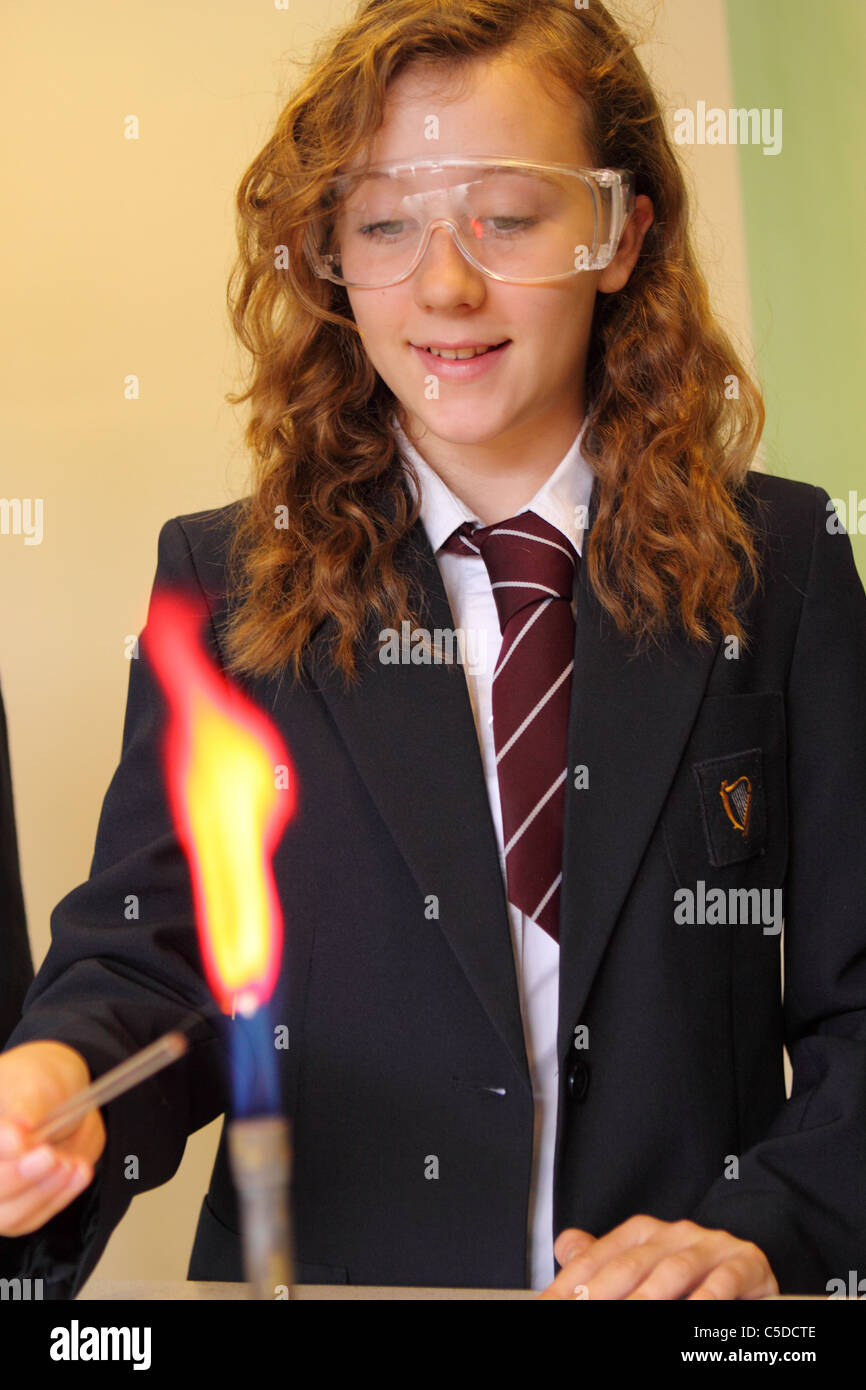La scuola secondaria una studentessa chemistry lezione con bunsen bruciatore di gas Foto Stock