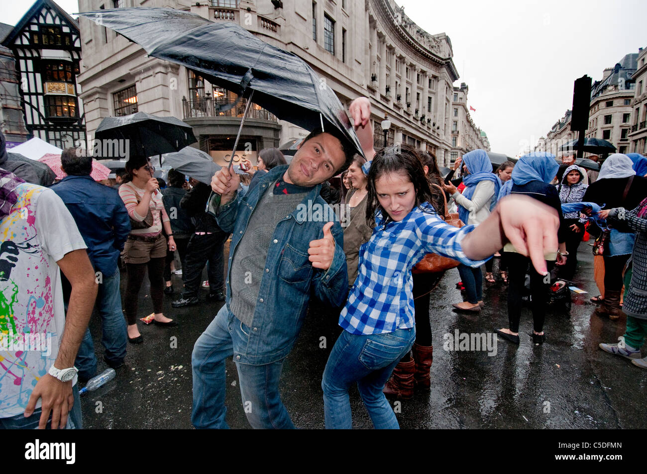 Le persone sotto gli ombrelloni in strada a Rainy day a Londra Foto Stock