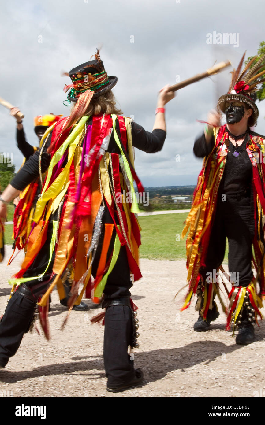 Black fronted Morris ballerini popolari, Wearring vestiti strappati. La  gente, indossando strisce di stoffa di colore arancione, nero e giallo che  si esibiscono al Tutbury Castle Weekend of Dance, Derbyshire, Regno Unito