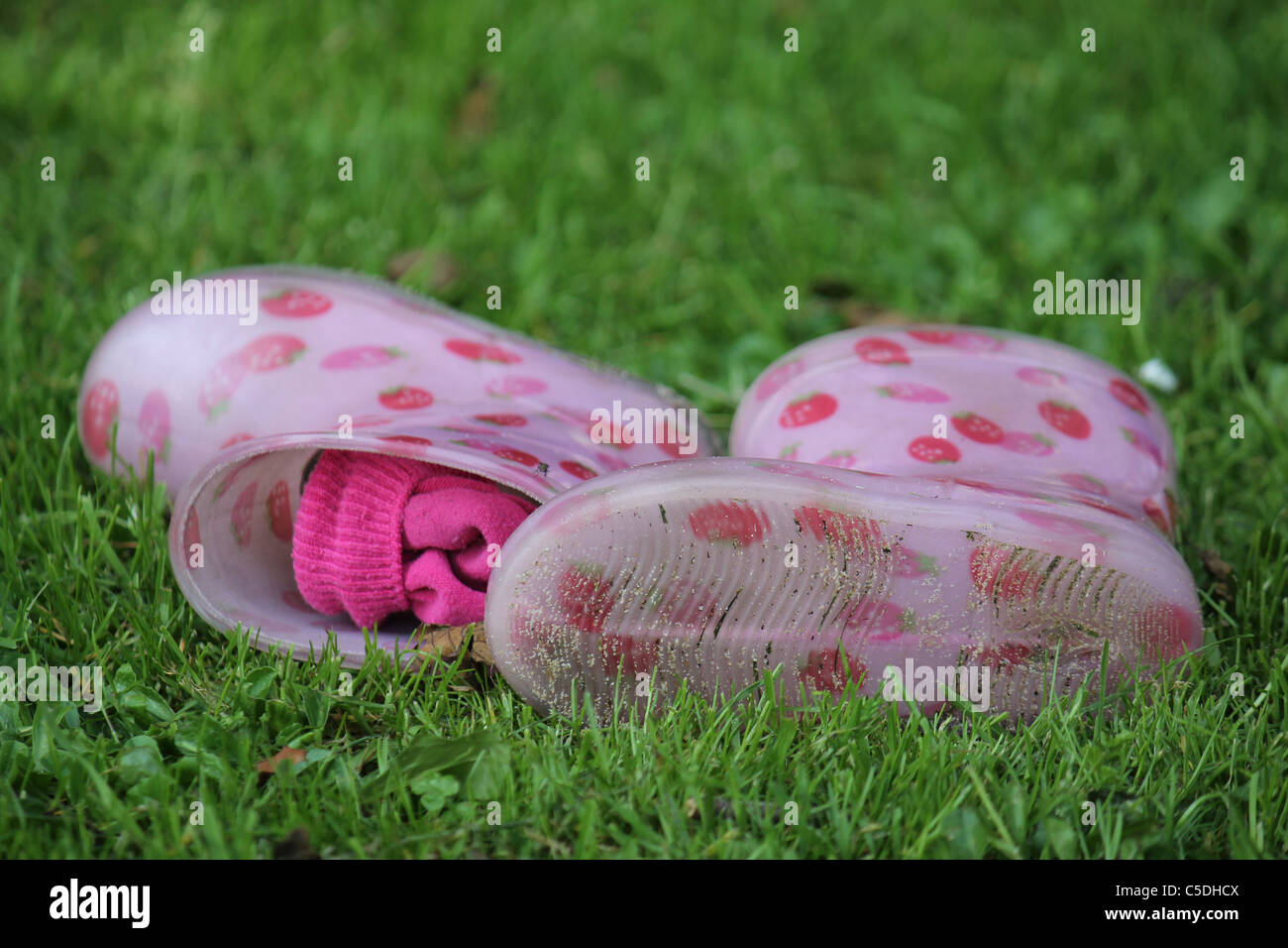 Due piccoli Fragola Rosa stivali di gomma in erba verde Foto Stock