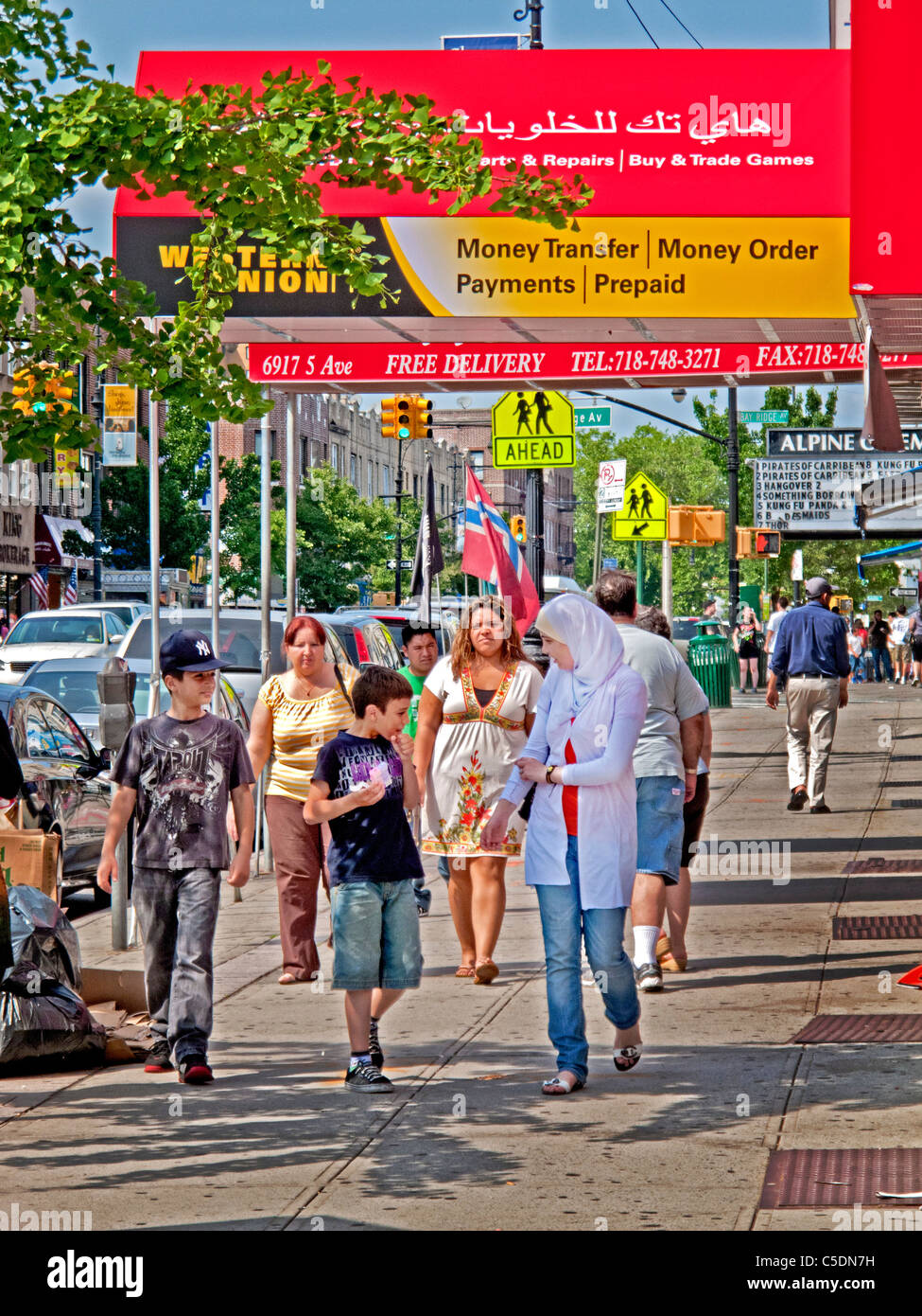 Un ragazzo musulmano in una testa sciarpa passa un bilingue Inglese/Arabo strada segno nel 'po' di Beirut sezione a Brooklyn, New York. Foto Stock