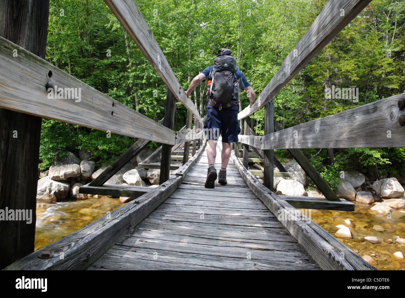 Pemigewasset deserto - un escursionista sulla passerella di legno che attraversa il ramo orientale del fiume Pemigewasset nel New Hampshire. Foto Stock