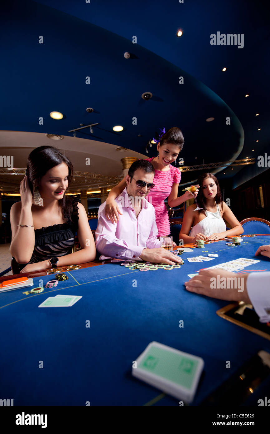 La gente seduta in un casinò e giocare a poker, Uomo con occhiali vincere Foto Stock