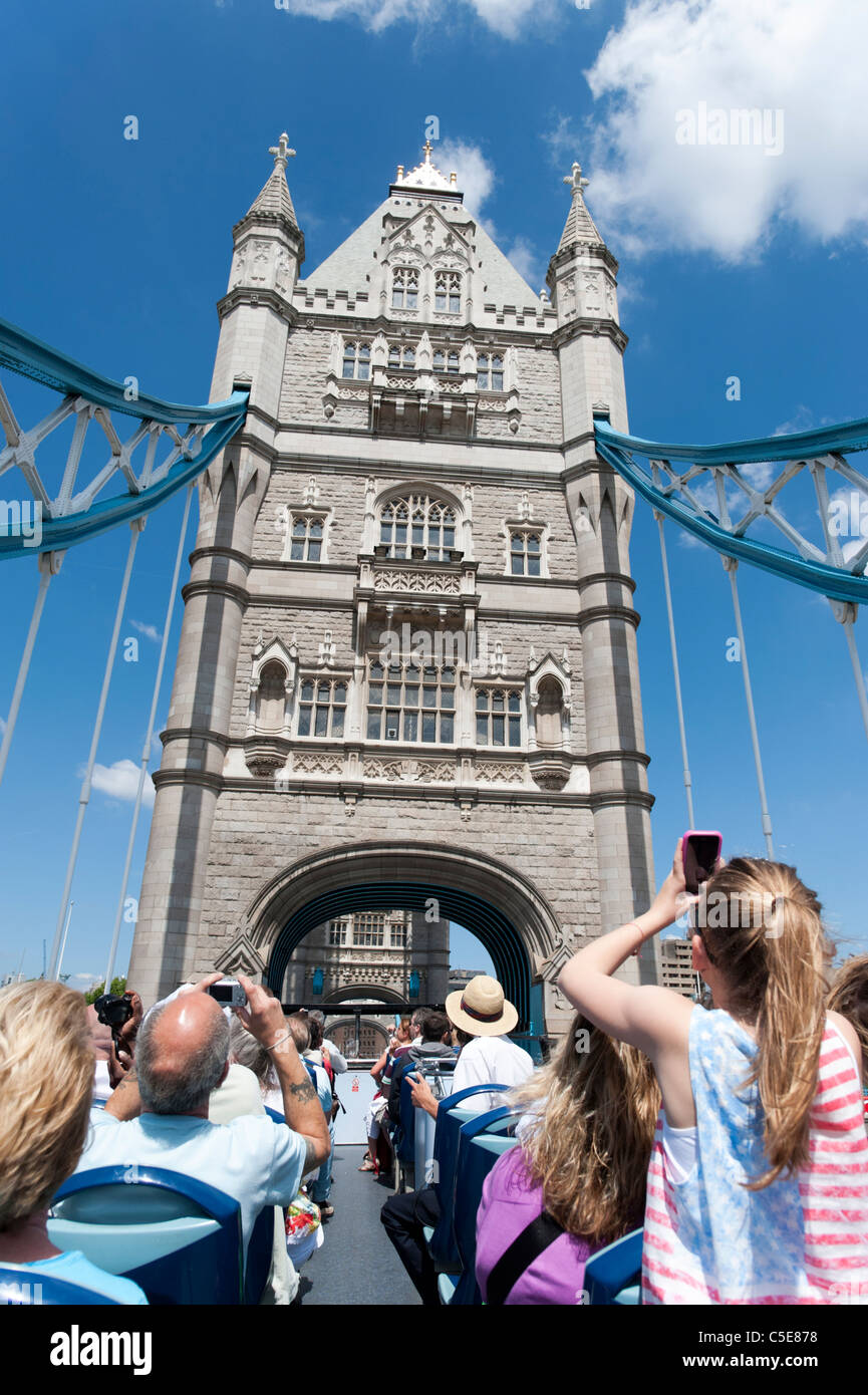 I turisti su open top double decker Londra Original Bus Tour attraversando il Tower Bridge di Londra, Regno Unito Foto Stock