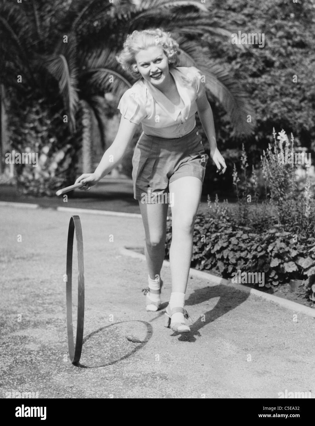 Giovane donna sorridente giocando con hoop Foto Stock