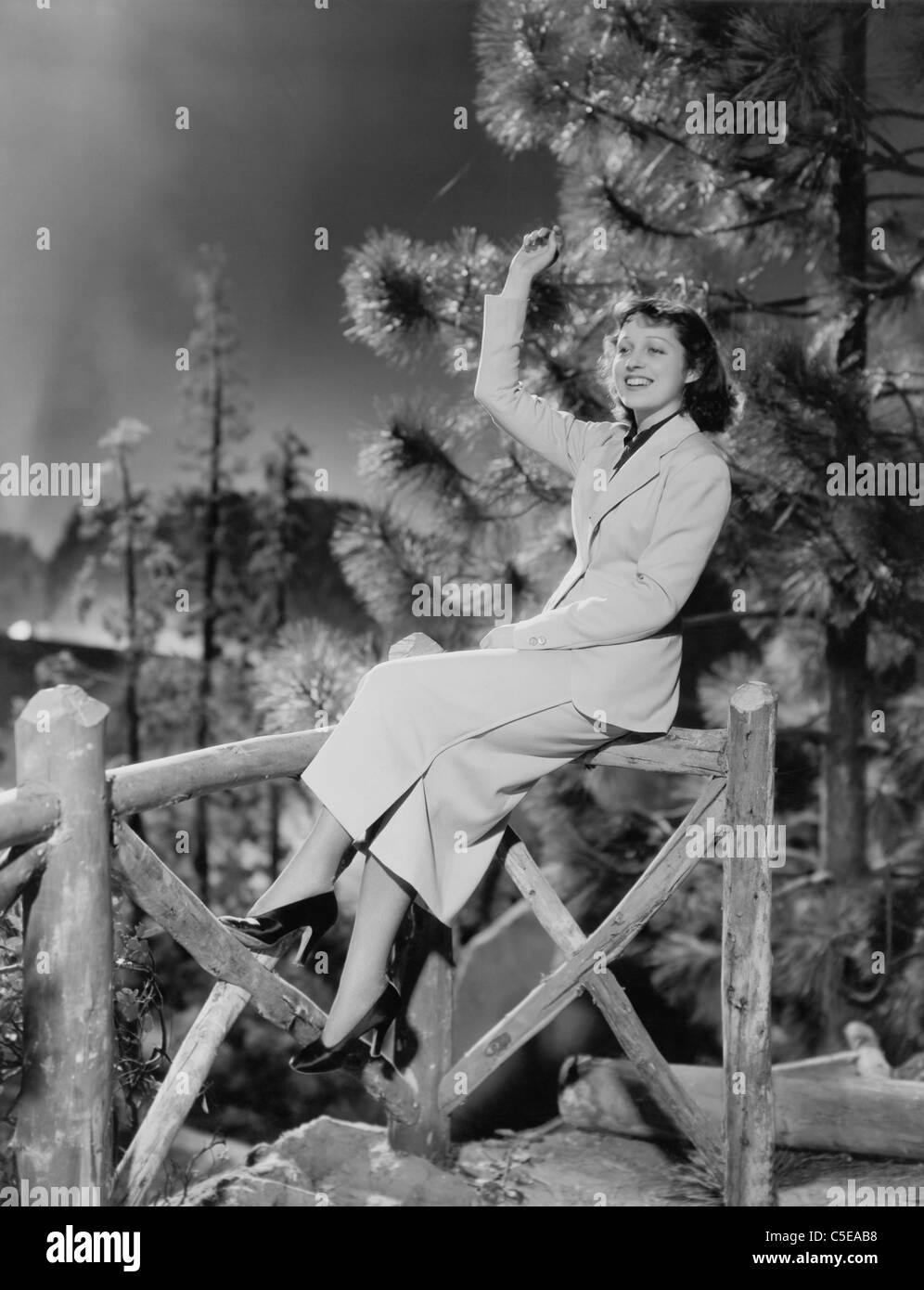 Donna seduta sulla ringhiera in legno Foto Stock