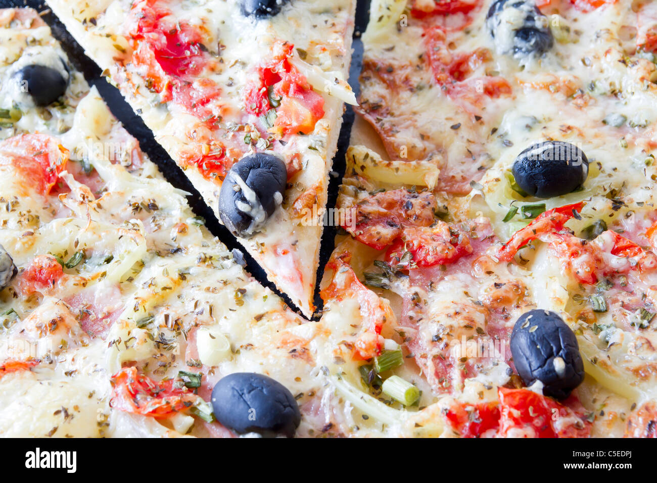 Pizza con mozzarella e pomodoro fresco e Pesto. Guarnito con Pomodoro Secco, verde e olive nere e basilico Lea Foto Stock