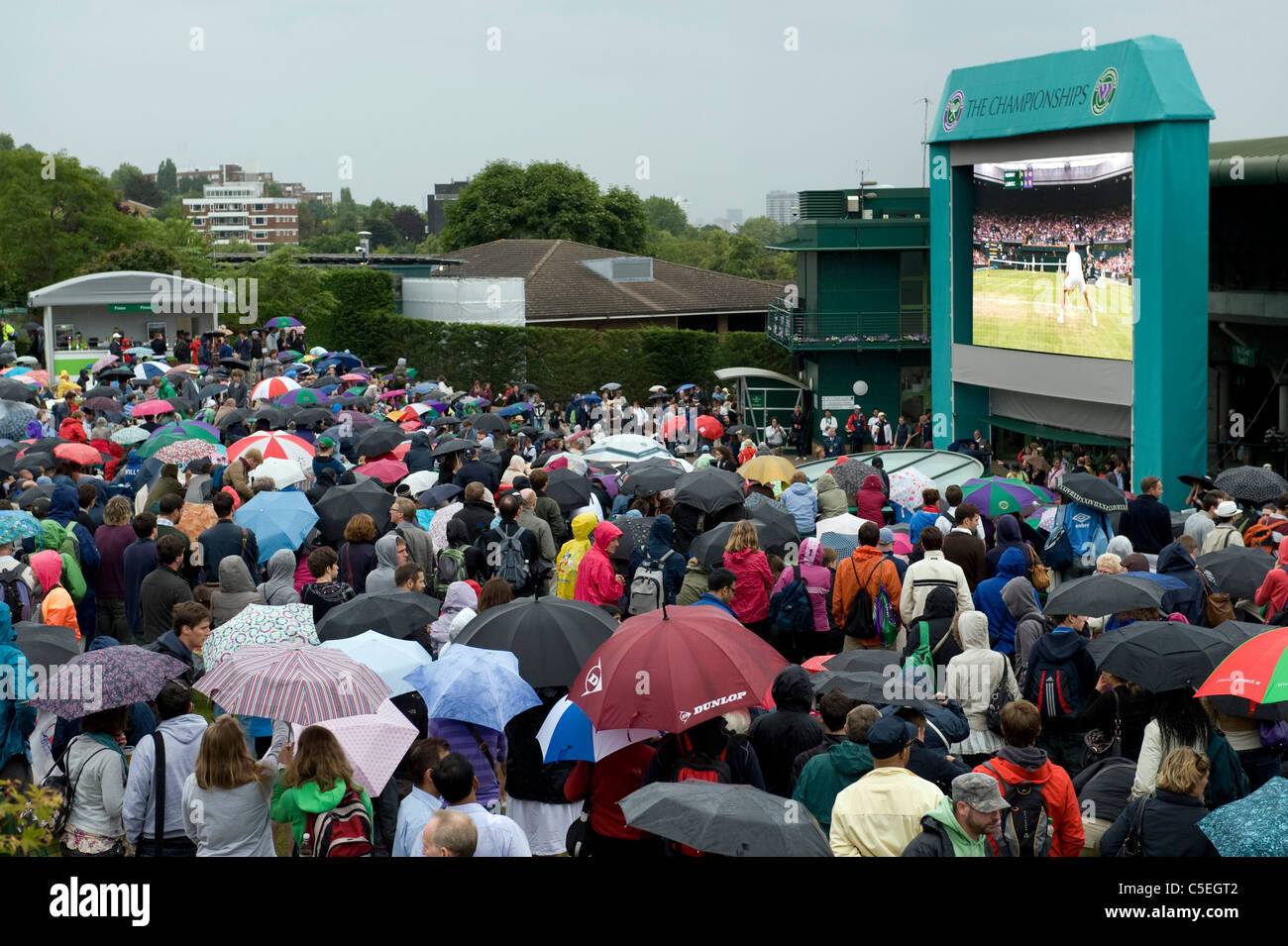 La folla guardare il grande schermo su Aorangi terrazza sotto la pioggia durante il 2011 Wimbledon Tennis Championships Foto Stock