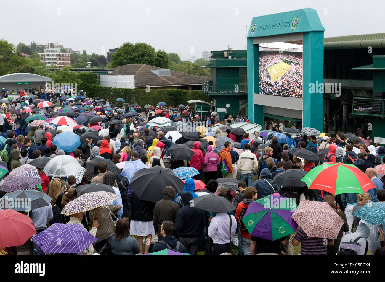 La folla guardare il grande schermo su Aorangi terrazza sotto la pioggia durante il 2011 Wimbledon Tennis Championships Foto Stock