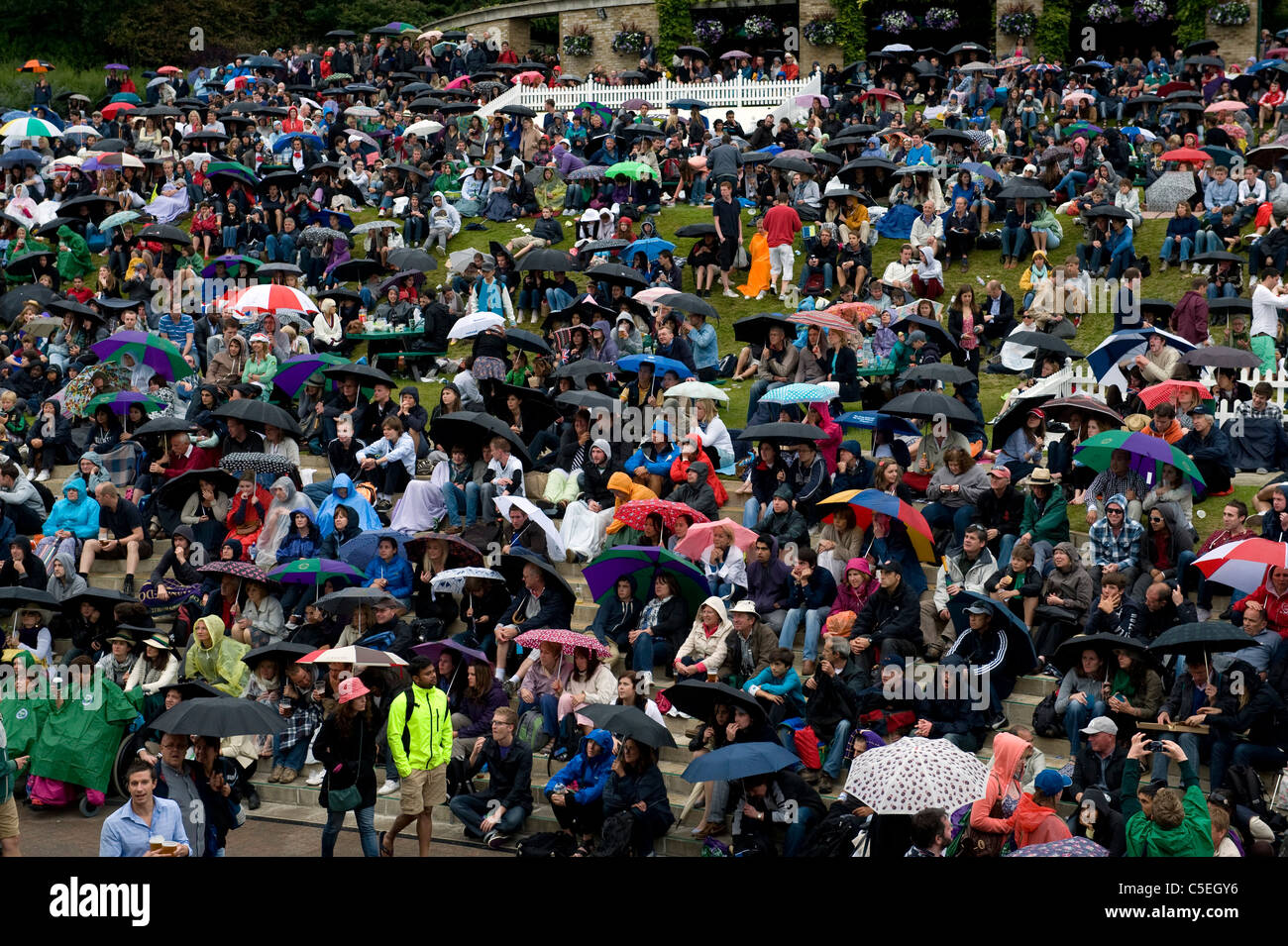 La folla guardare il grande schermo su Aorangi terrazza sotto la pioggia durante il 2011 Wimbledon Tennis Championships Foto Stock