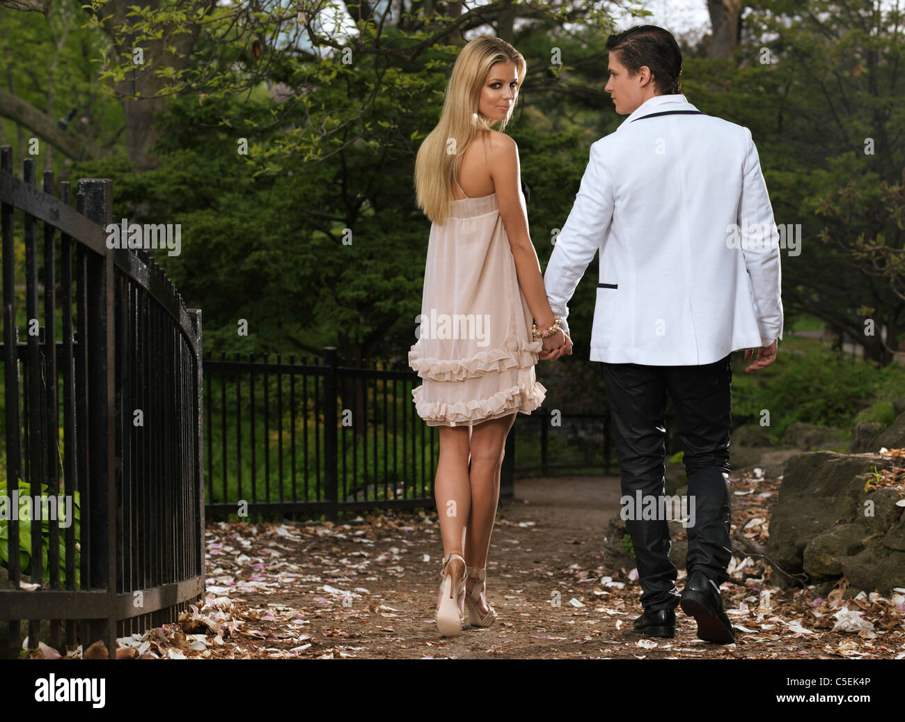 Licenza e stampe alle MaximImages.com:00 - giovane coppia romantica a piedi attraverso un parco tenendo le mani. Primavera panoramica. Foto Stock