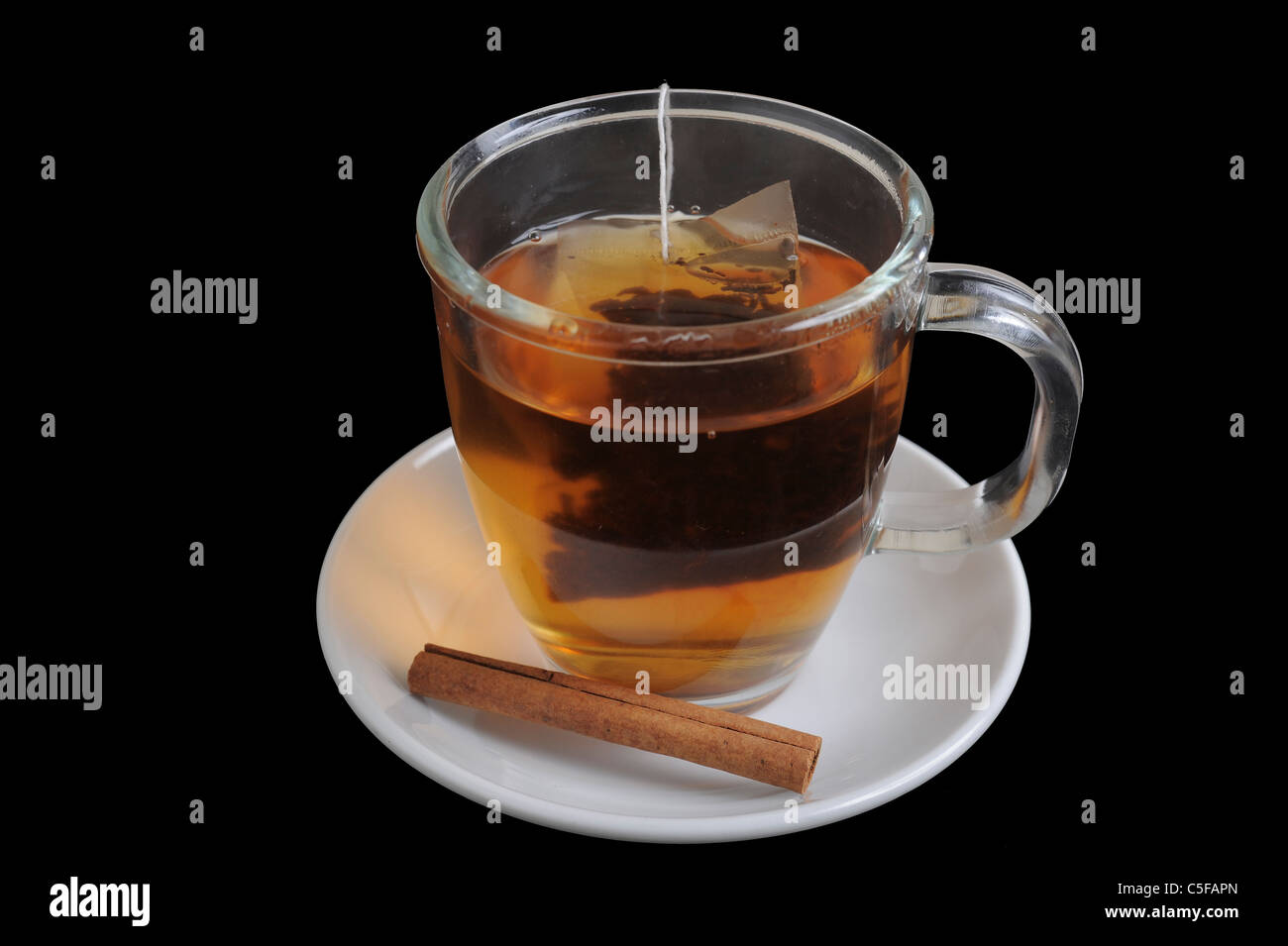 Una tazza di acqua calda tè nero con cannella su sfondo nero Foto Stock