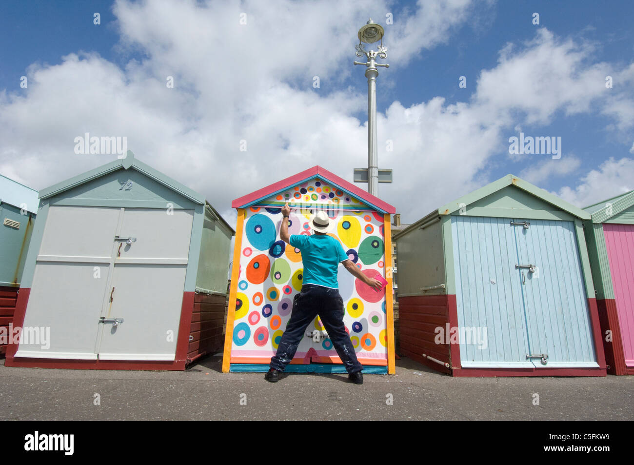 Un uomo di mezza età che sfidano le regole lui e la sua pittura Brighton Beach Hut in non-regolamento macchie colorate. Foto Stock