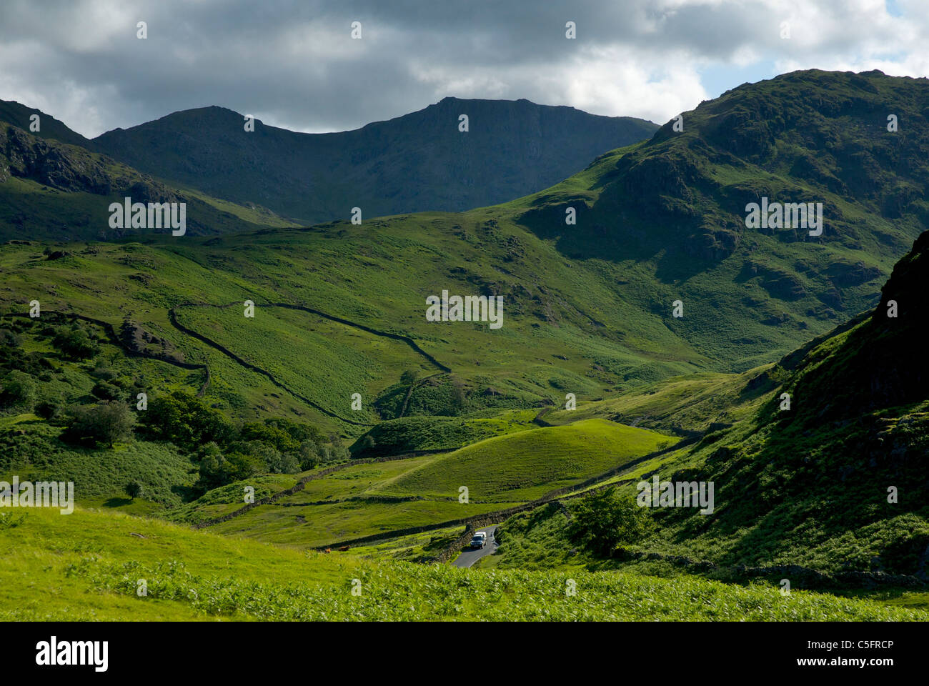 Little Langdale valley, Parco Nazionale del Distretto dei Laghi, Cumbria, Regno Unito Inghilterra, con auto provenienti di discesa lungo il ripido Wrynose Pass Foto Stock