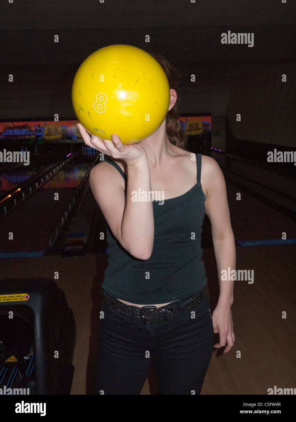 Una giovane donna con un giallo ten pin bowling palla Foto Stock