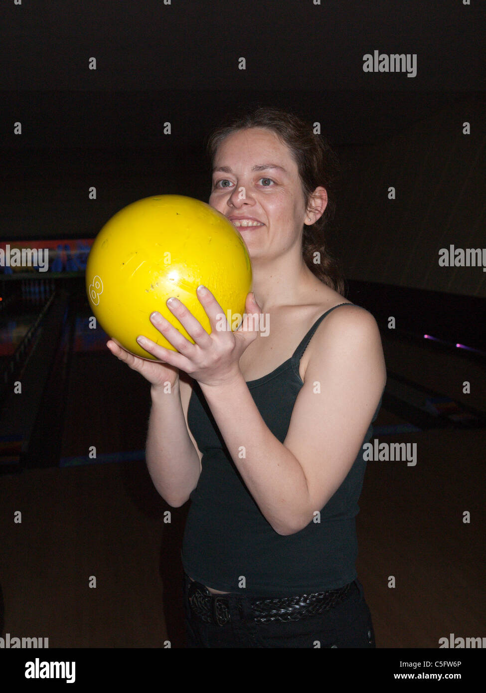 Una giovane donna con un giallo ten pin bowling palla Foto Stock