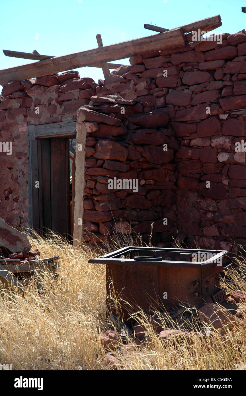 Un bacino di ferro si siede di fronte a un agriturismo in avanzato stato di decadimento in Cuervo New Mexico. Foto Stock